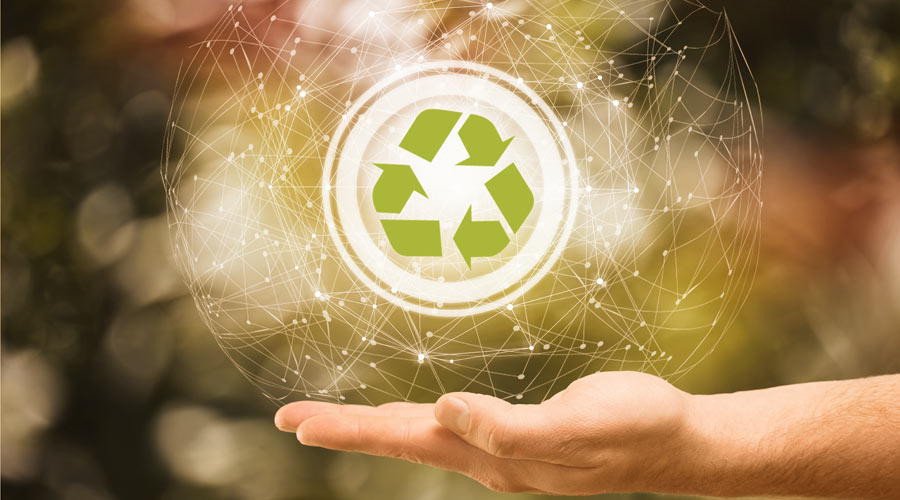 Tecnologia e meio ambiente: mão aberta sob um fundo com tons predominantemente verdes, e acima dela uma forma circular. Dentro dessa forma está o símbolo da reciclagem.